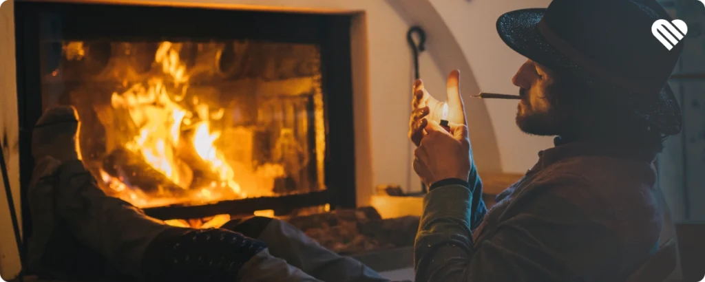 comfortable man lighting a joint in front of the fireplace